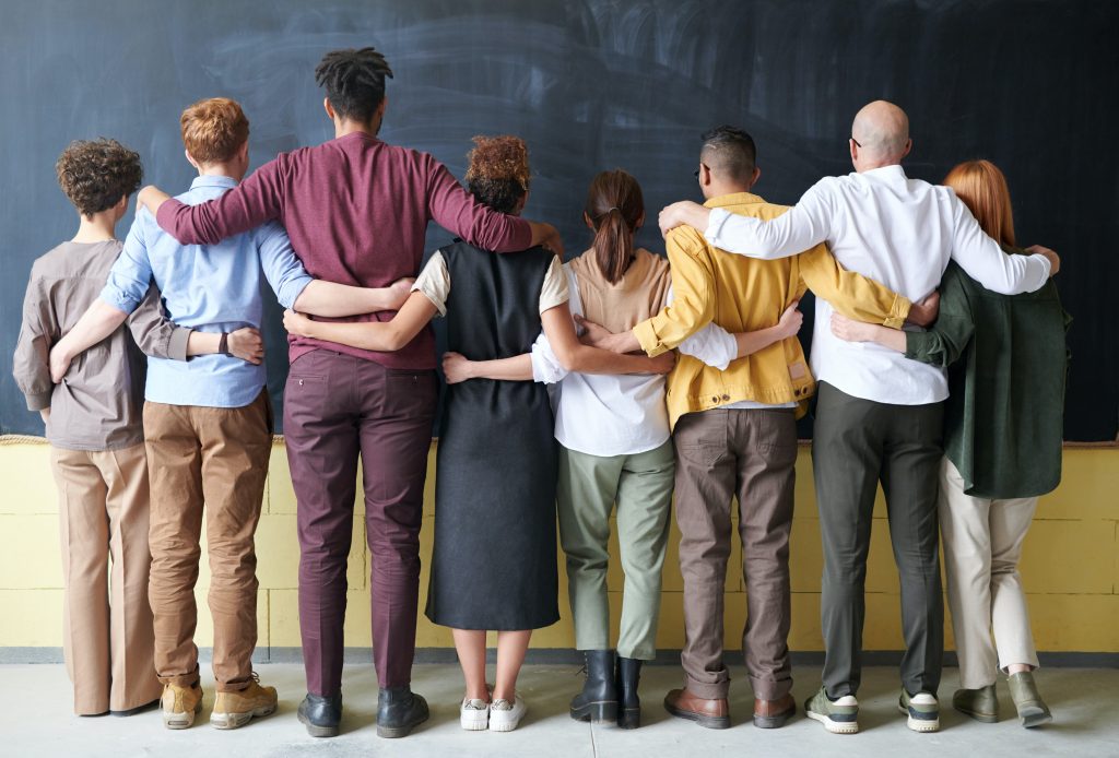 8 employees embrace each other while looking at the wall to represent employee engagement.