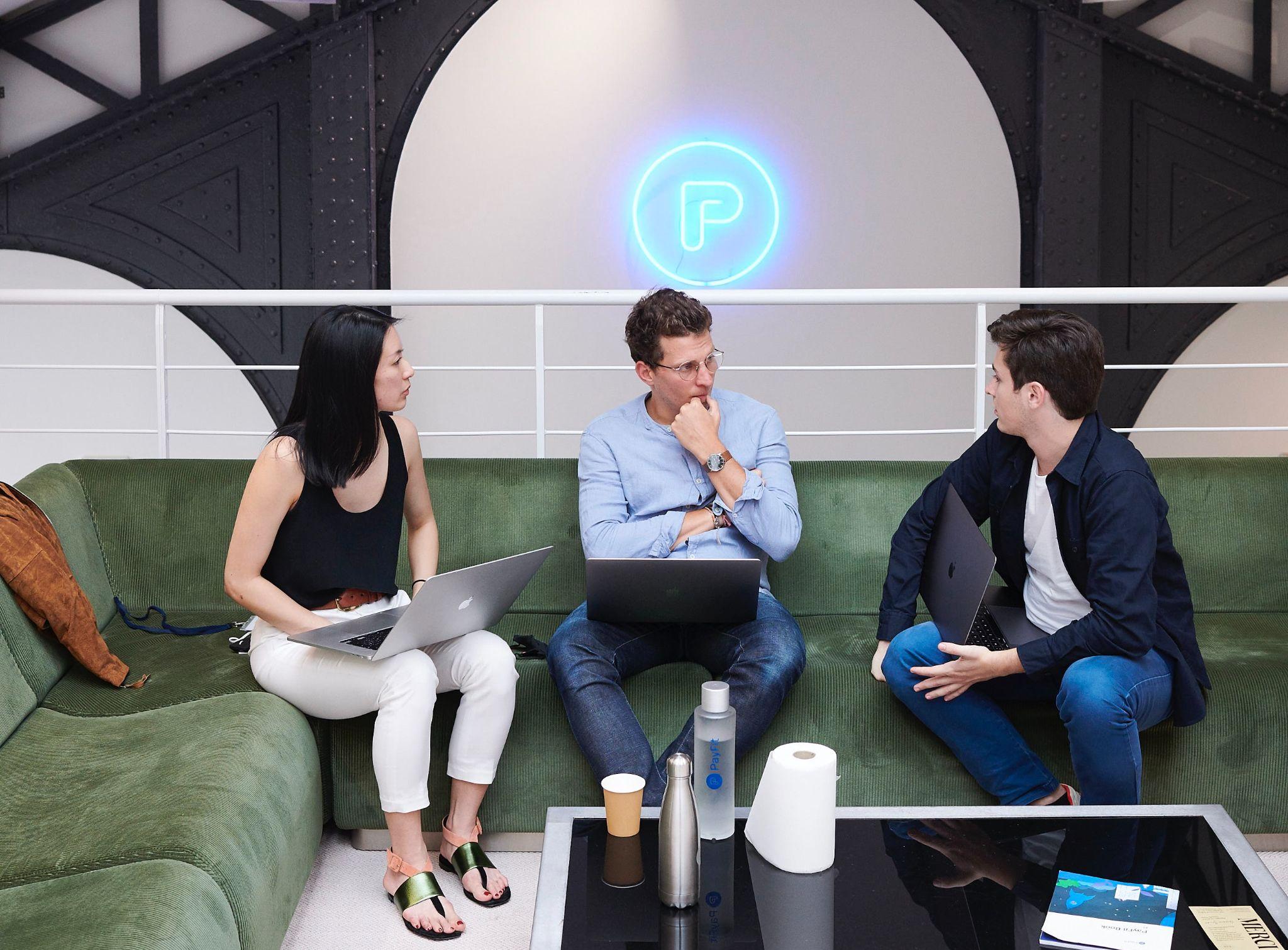 3 employees talking at PayFit's office.
