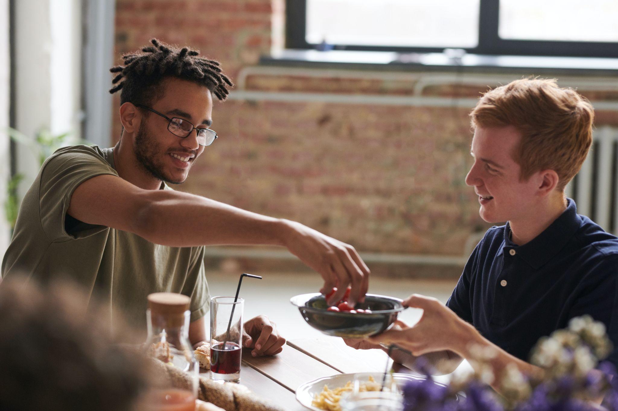 2 diverse employees share food at work.