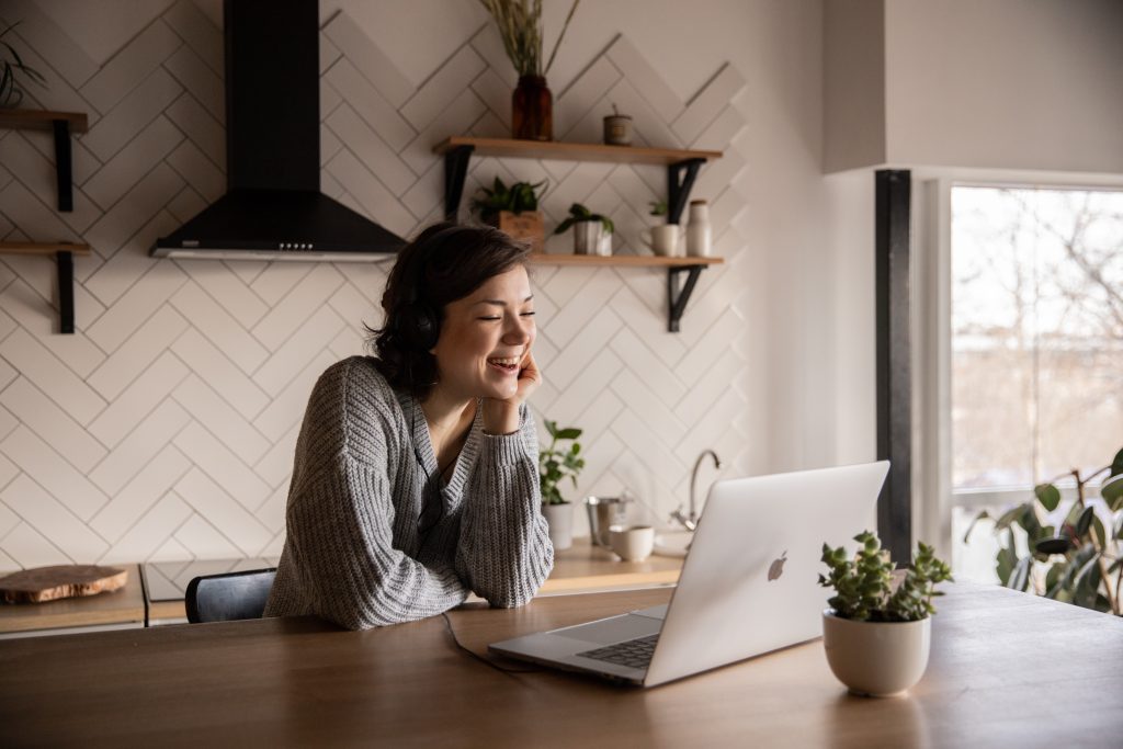 Employee smiles at her computer while working from home.