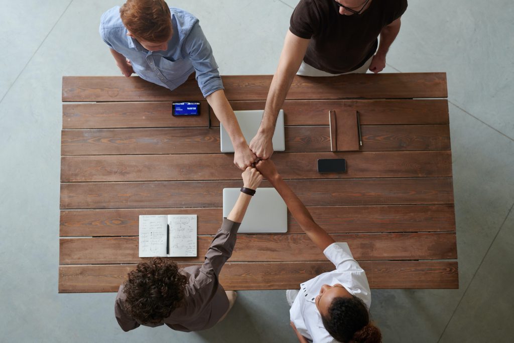 4 employees fist bump as celebration.