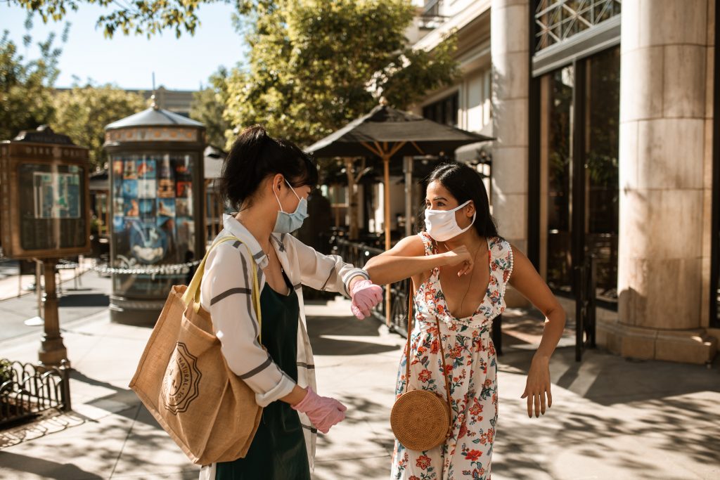 2 friends say hello in the street by bumping their elbows.