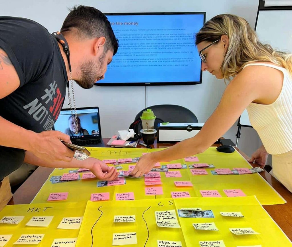 Dos empleados de colppy trabajando en una dinámica de canva con postit