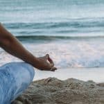 A woman doing yoga on the beach a great wellness program to relax and enhance mental health