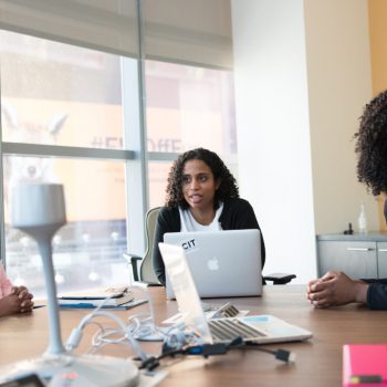 Three female coworkers sitting at the table talking and smiling