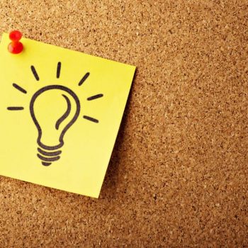 Un post-it con una bombilla dibujada clavado en una pizarra de corcho.