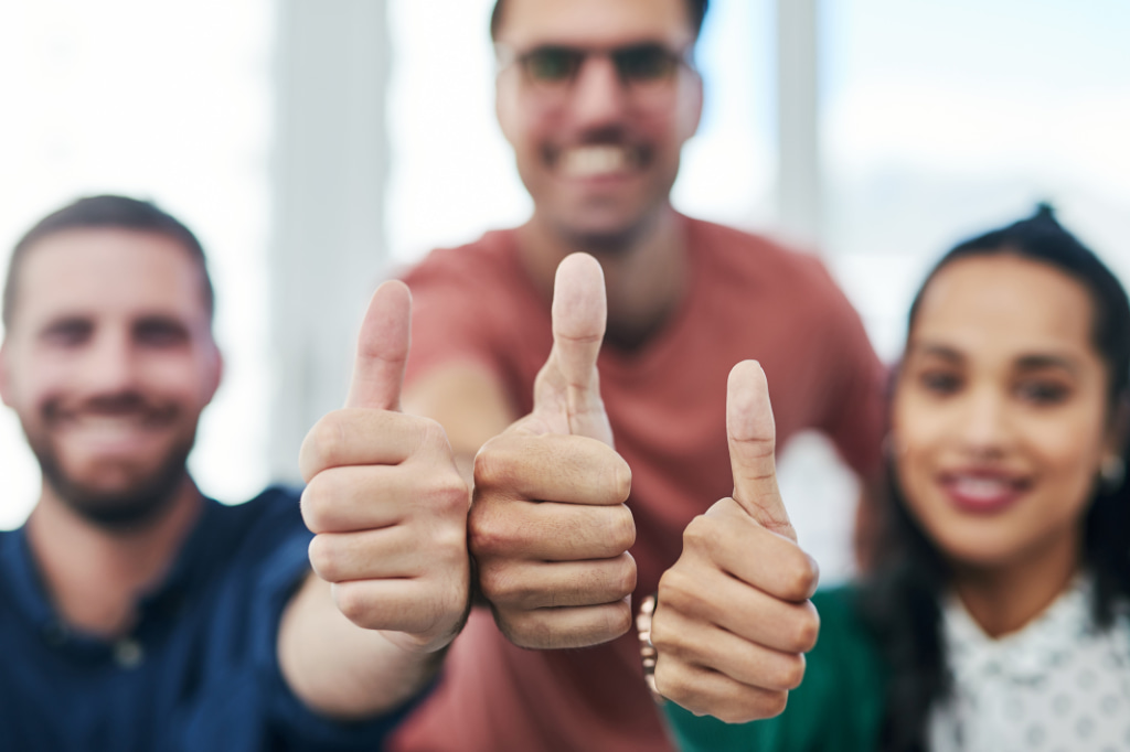 Tres empleados dando feedback positivo a un compañero que no se ve desde la imagen